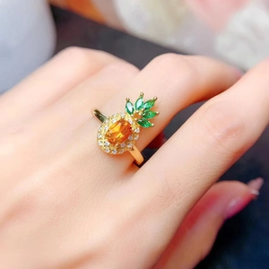 Close-up of golden pineapple ring featuring yellow gemstone and green crystal leaves