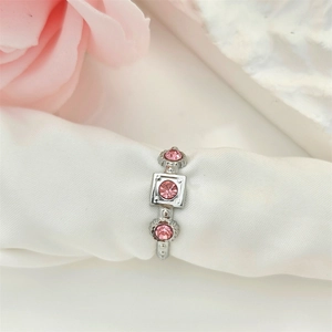 Irregular silver geometric ring with three pink crystals on white silk background