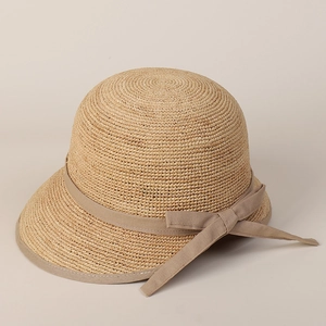 Detail of raffia sun hat with light brown bow ribbon and elegant drooping brim