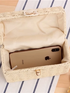 Woven straw box bag with gold metal clasp showing internal capacity for a smartphone