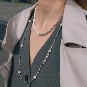 Detail of silver OT buckle pearl necklace and mixed link chain worn by a model