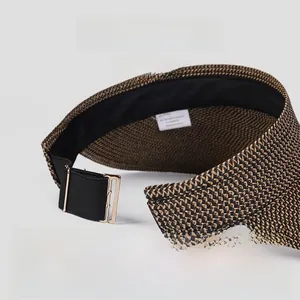 Detail of grey straw sun visor featuring large brim and adjustable golden buckle