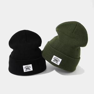 Black and olive green knit Brooklyn beanies with woven patch shown in a front-view layout