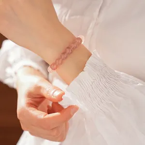 Pink strawberry quartz beaded bracelet shown on wrist with elegant white shirt sleeve