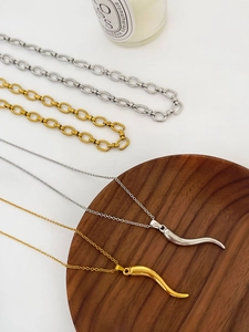 Italian horn and chili pendants on gold and silver chains in a wooden tray
