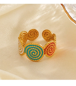 Detail of golden spiral enamel ring with teal and magenta accents on silk background