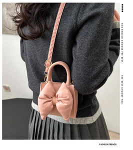 Detail view of a pink bow shoulder bag worn by a model in a trendy fashion outfit