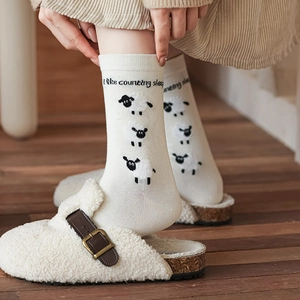 Chaussettes mi-mollet tricotées crème avec motif mouton et slogan sur parquet