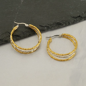 Macro detail of twisted multi-layer hoop earrings in gold and silver finish