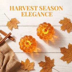 Set of two glowing orange pumpkin LED lights with autumn leaves on white wood surface