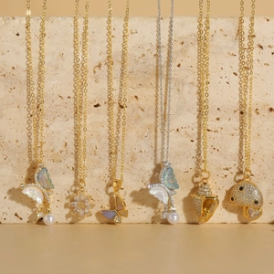 Exquisite pearl necklaces with butterfly shell and flower pendants on stone background