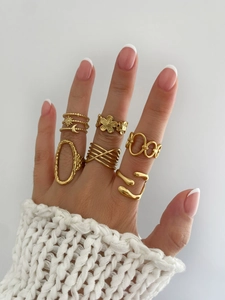 Detail of gold plated geometric rings set featuring moon, sun, and flower motifs on fingers