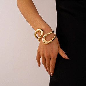 Dettaglio del bracciale rigido dorato lucido con design geometrico traforato