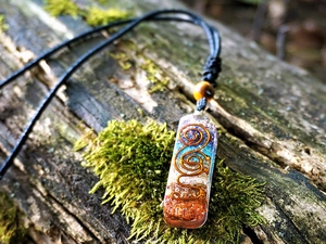 Macro shot of Orgonite pendant with mixed gemstones and copper wire on mossy bark
