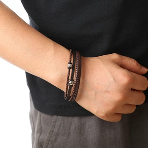 Close-up of layered brown braided leather bracelet with metal beads on male wrist