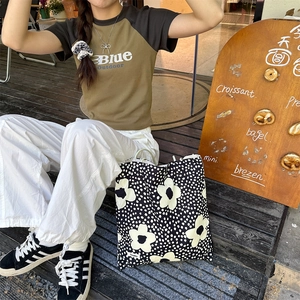 Détail du sac cabas en toile à motif floral noir et blanc dans un cadre de vie en plein air