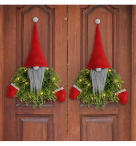 Close-up of LED glowing Christmas gnome wreaths on dark wooden doors for festive decoration