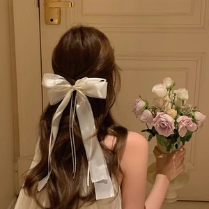 Barrette à cheveux élégante en soie blanche avec glands perlés portés par un mannequin