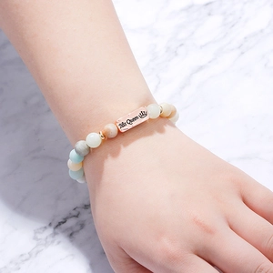 Detail of beaded bracelet with His Queen engraved rose gold plaque on model wrist