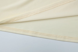 Λεπτομέρεια ραφής overlock και στρίφωμα σε μπεζ ύφασμα φορέματος με έξω τους ώμους