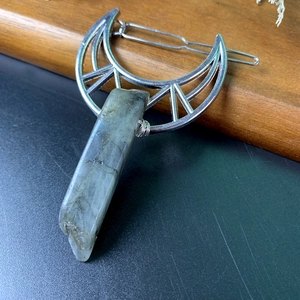Close-up of handmade crescent moon hair clip with natural labradorite stone and wire wrapping