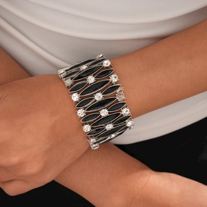 Dettaglio di tessere nere a rombo e cristalli su un ampio bracciale elastico alla moda