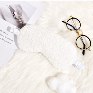 Detail of white plush sleep mask with elastic strap on a cozy soft background
