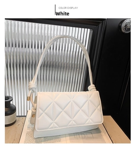 Detail of white quilted leather bag showing gold hardware and knot handle design