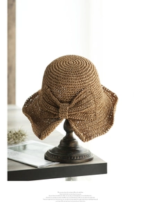 Detalle de sombrero de paja con lazo grande colocado sobre un soporte de madera retro