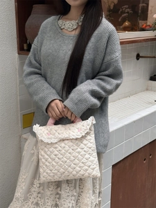 Detailed view of cream quilted laptop bag with floral patterns and lace trim handles
