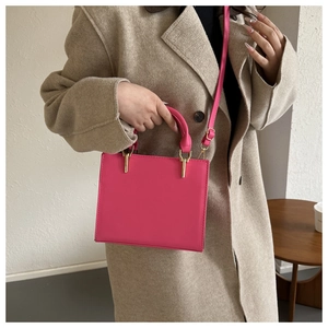 Detail of trendy bright pink rectangle handbag with gold hardware and smooth leather finish