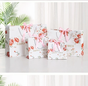Detail of four floral marble gift bags with pink ribbon handles and Happy Times gold foil