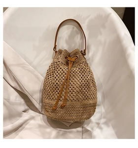 Detail view of woven paper rope bucket bag with faux leather strap and drawstring closure