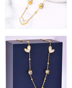 Detail of gold titanium steel necklace with white heart shells and zircon cylinder charms