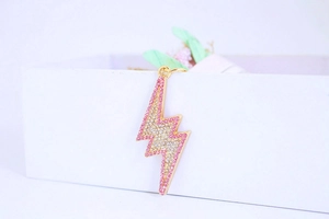 Detail of a gold lightning bolt keychain with pink rhinestones on a white box