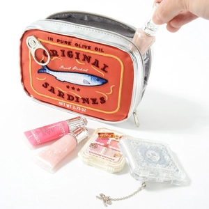 Creative sardine tin makeup bag in orange with a hand placing cosmetics inside