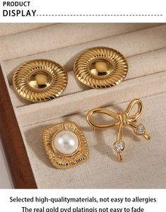 Détail de bijoux plaqués or PVD incluant broche nœud et boucles en boîte velours
