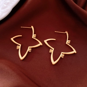 Macro shot of 18K gold plated star-shaped dangle earrings on red silk fabric background