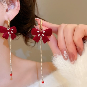 Detail view of burgundy flocked bow earrings with rhinestone tassels on a model
