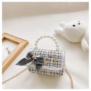 Detailed macro view of tweed girls handbag with elegant pearl handle and metal bow charms