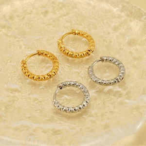 Détail de boucles d'oreilles créoles texturées en or 18K et argent sur plateau