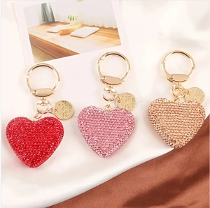 Sparkling rhinestone heart keychains in red, pink and gold on elegant silk backdrop