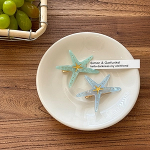 Detail view of acrylic starfish hair clips with marble texture on a ceramic plate