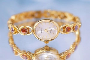 Close-up of golden quartz bracelet watch with colorful gemstone accents and a round dial