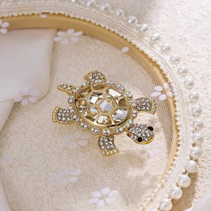 Close-up of golden turtle brooch with large transparent crystal and sparkling rhinestones