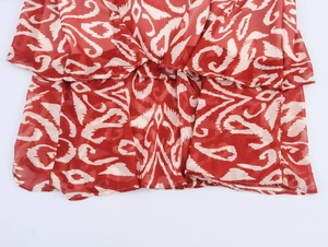 Détail de robe longue en mousseline rouge avec imprimé géométrique et volants étagés