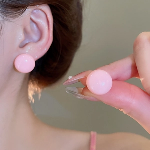 Close-up of minimalist peach pink round stud earrings in smooth glossy resin finish