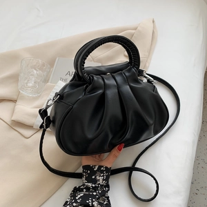 Minimalist black pleated cloud shoulder bag with adjustable strap on a stylish background