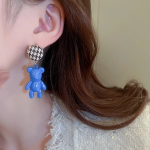 Detail shot of a model wearing blue flocked bear earrings with houndstooth studs