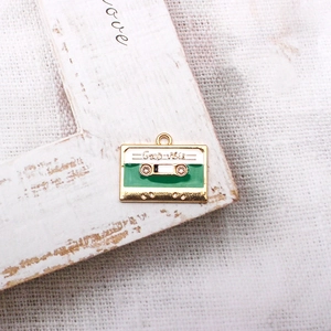 Detail of retro cassette alloy pendant in gold and green finish with Good Vibes engraving